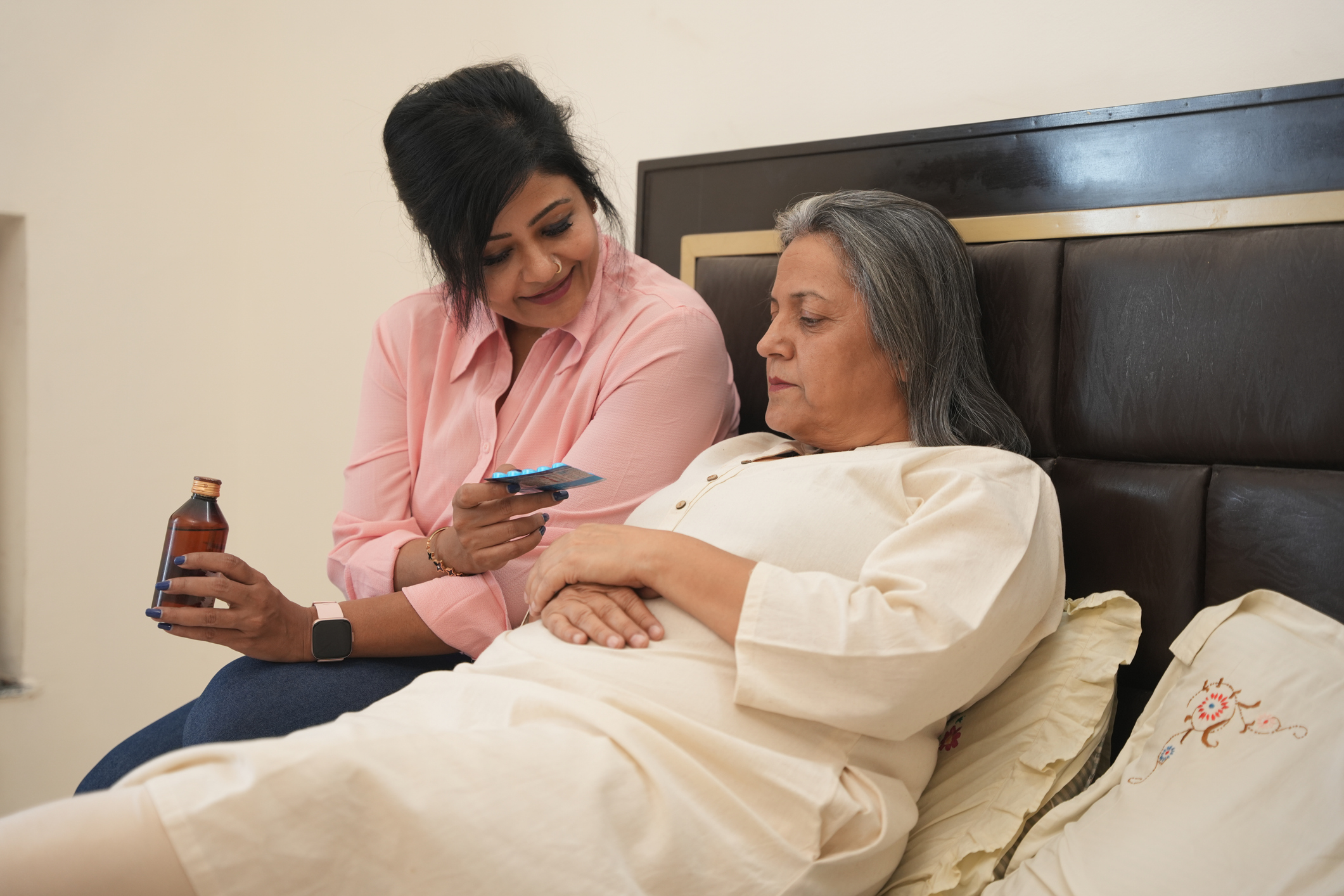 young indian daughter giving medication supplement to her ill mother. healthcare concept. Zorghandeling mantelzorger